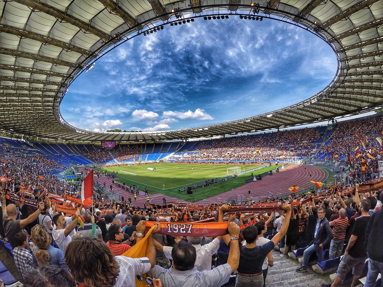 Des supporters agitent leurs écharpes dans les tribunes d’un grand stade de football