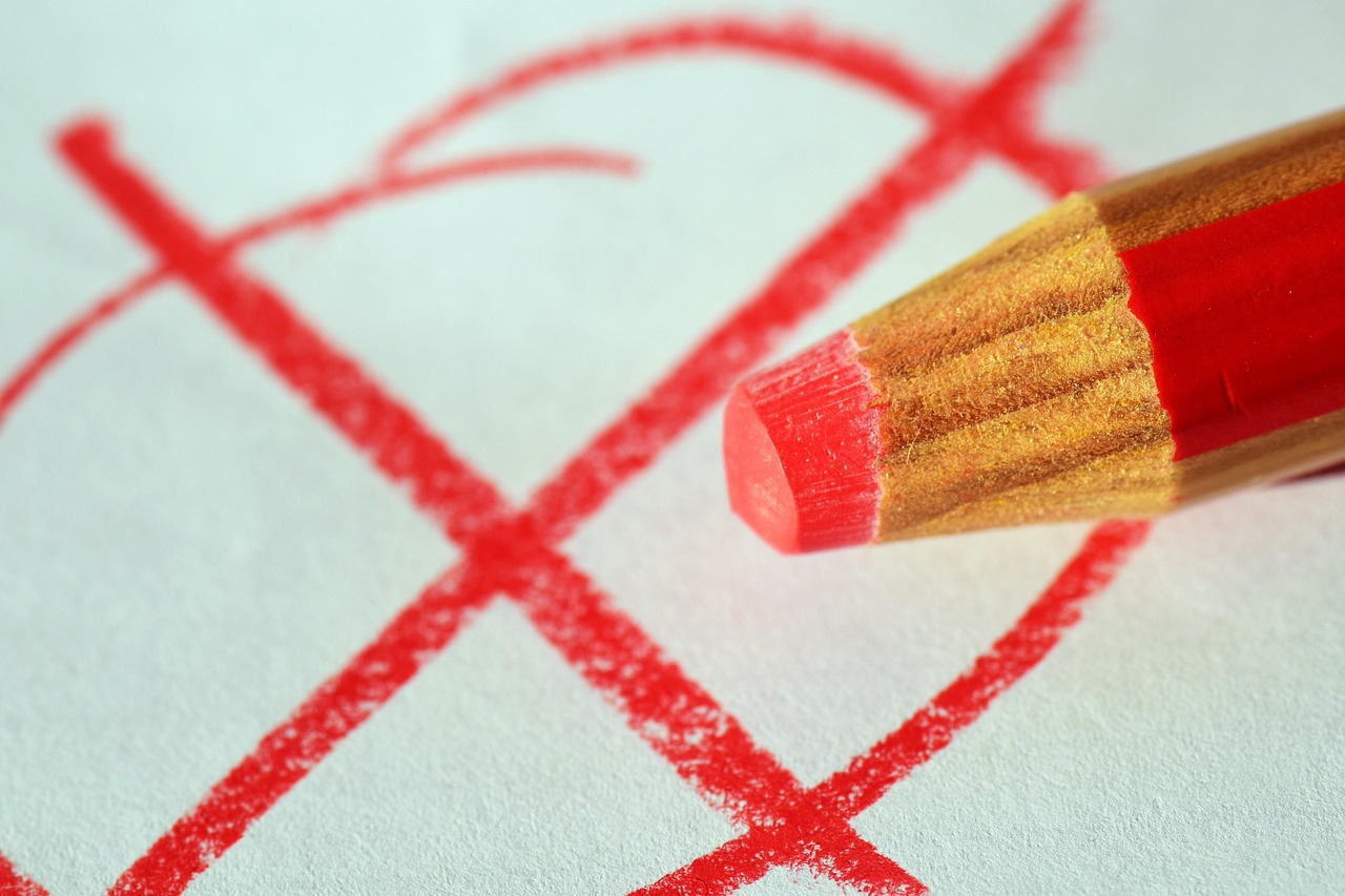 Une croix tracée au crayon rouge sur une feuille blanche